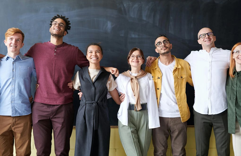 a team happily standing side by side, showcasing why consistency is key to running a business