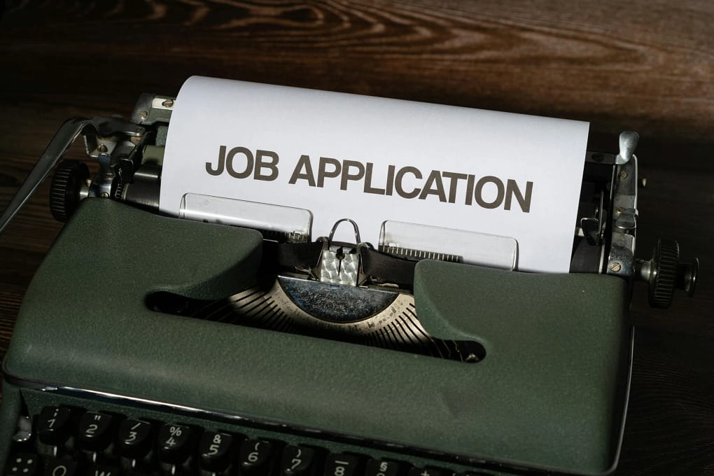 a typewrite with the words "job application" typed on a piece of paper, emphasizing how disc communication styles are crucial in hiring