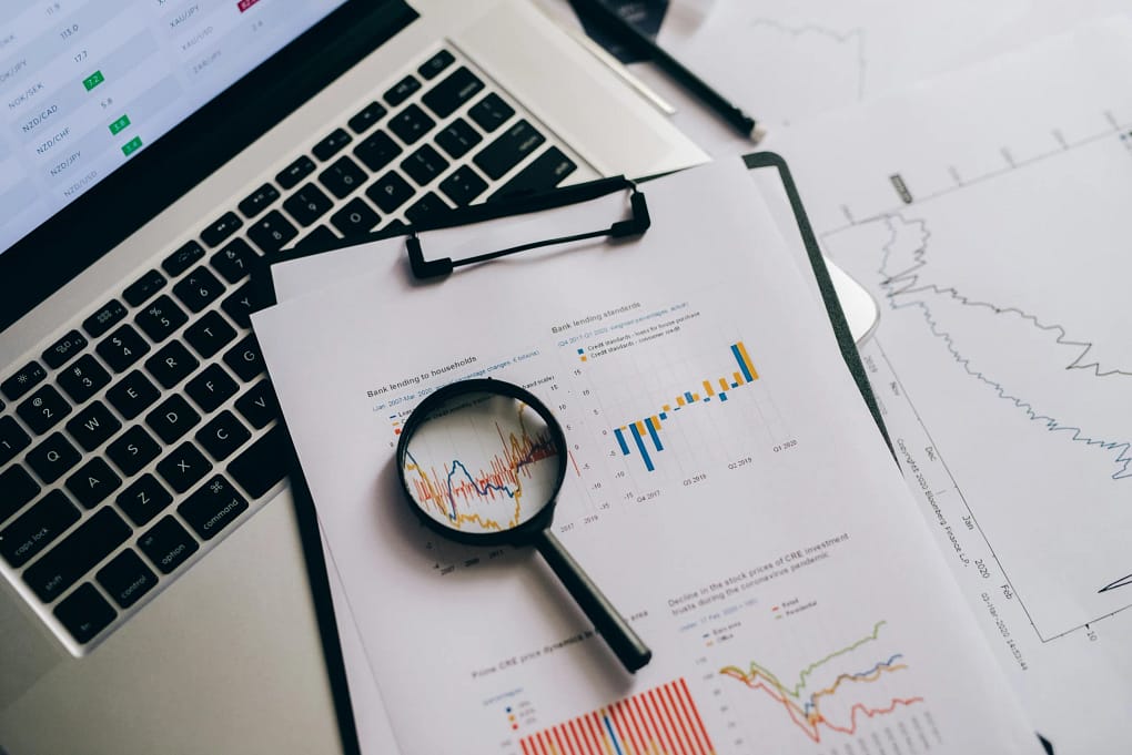 a printed copy of stock market trends projections scrutinized with a magnifying glass