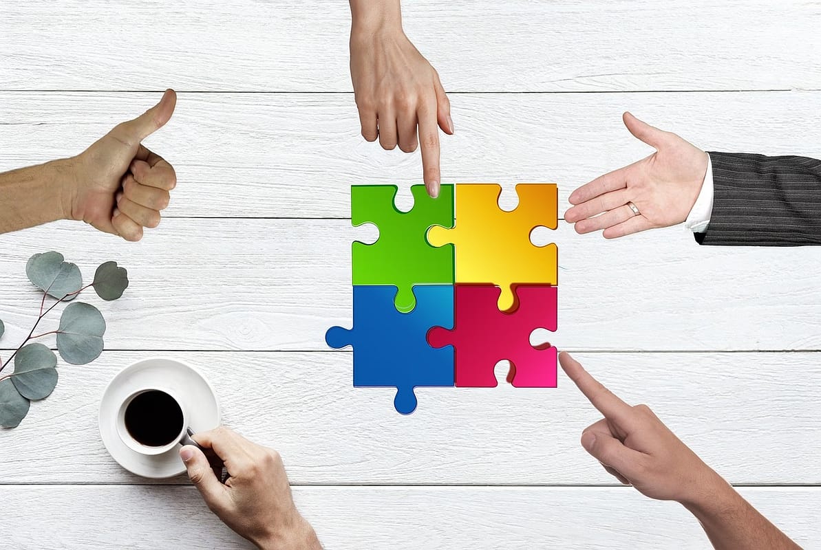 puzzle pieces joining together smoothly surrounded by gestures of approval as a sign of a successful post-merger integration