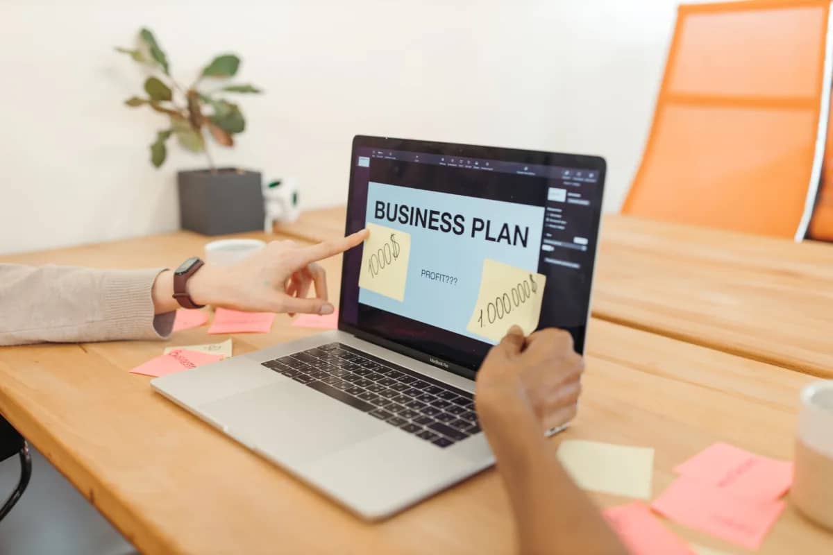 business leaders discussing a presentation on a laptop with the prominent words "business plan"