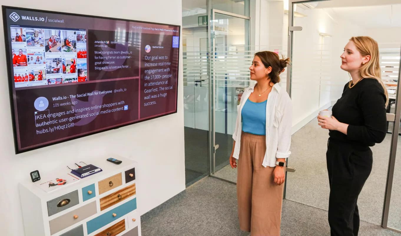 employees looking at a big screen showing a "social wall", one of the many applications of AI for companies