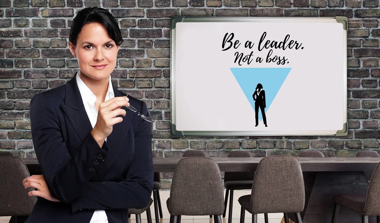 a businesswoman in from of the sign depicting good leadership skills. The sign says "be a leader, not a boss"