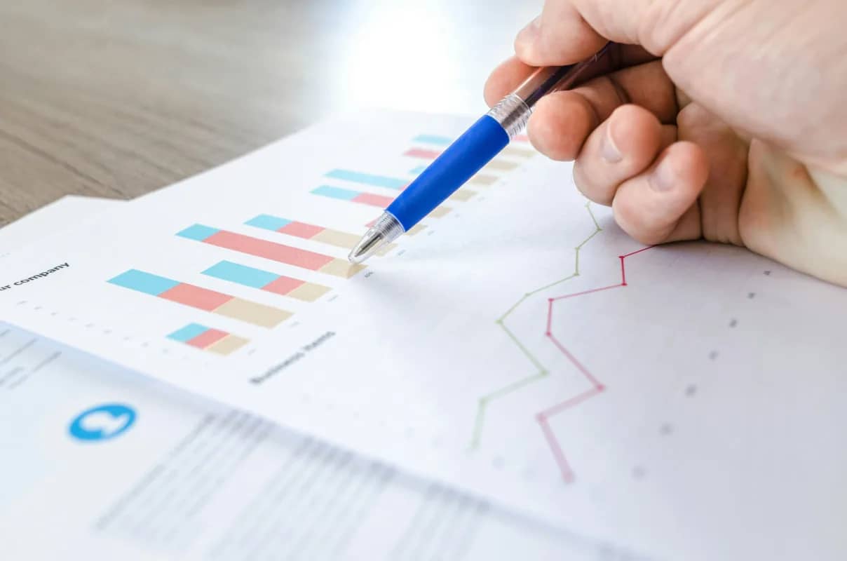 a hand holding a pen while analyzing data for strategic management