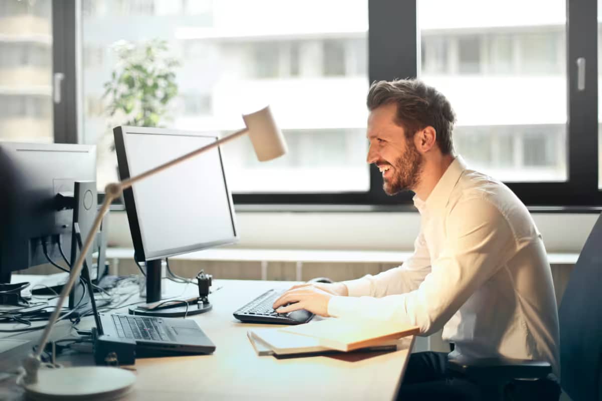 a man smiling in front of a computer monitor