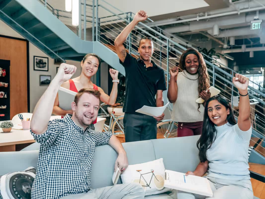 a roomful of motivated employees raising their fists as a gesture of victory