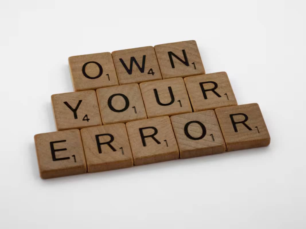 scrabble pieces laid out to spell "own your error"