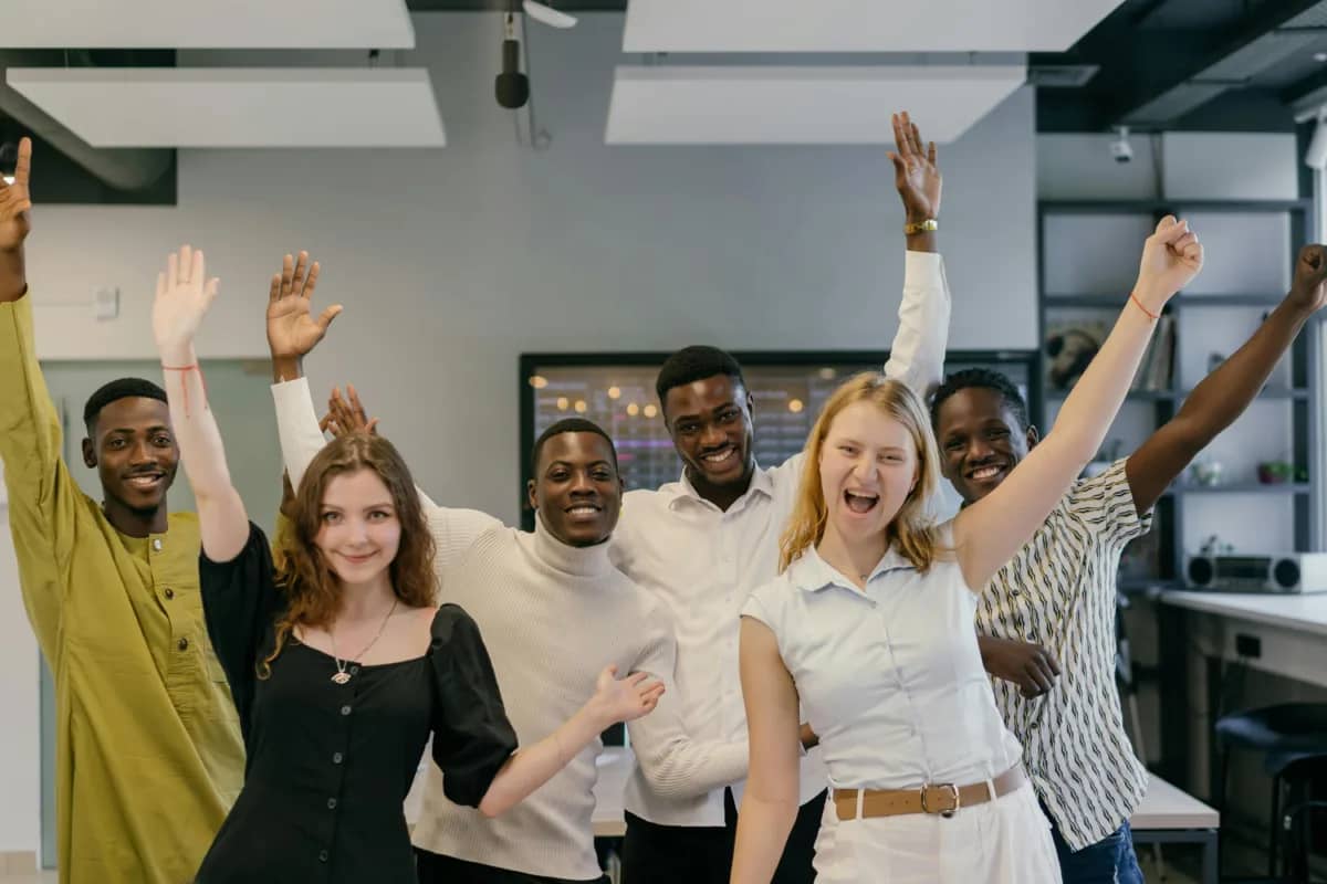 team members happily raising their hands as a result of a good company culture