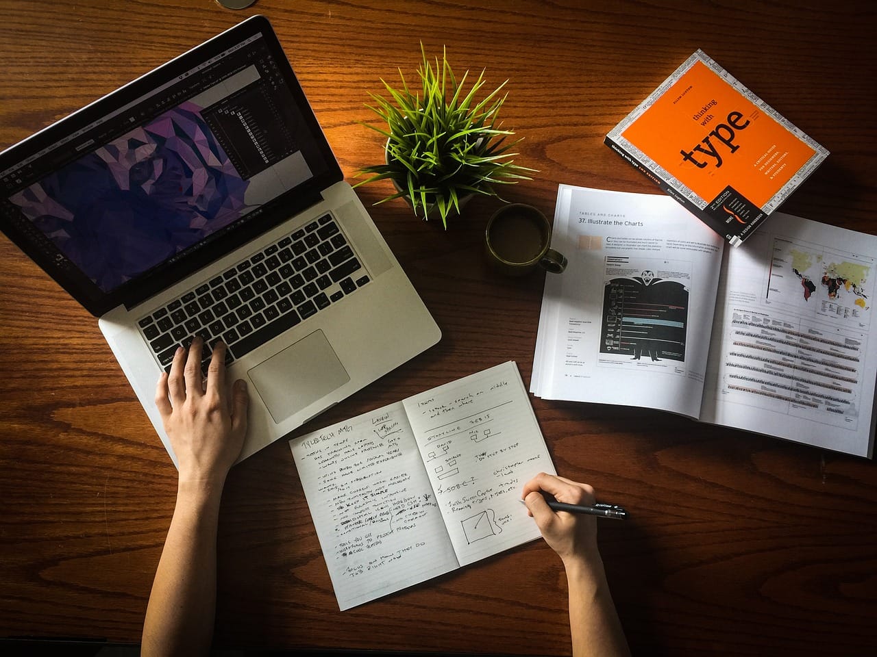 a photo of a workspace of someone problem-solving and decision-making: a laptop, a notebook, and books